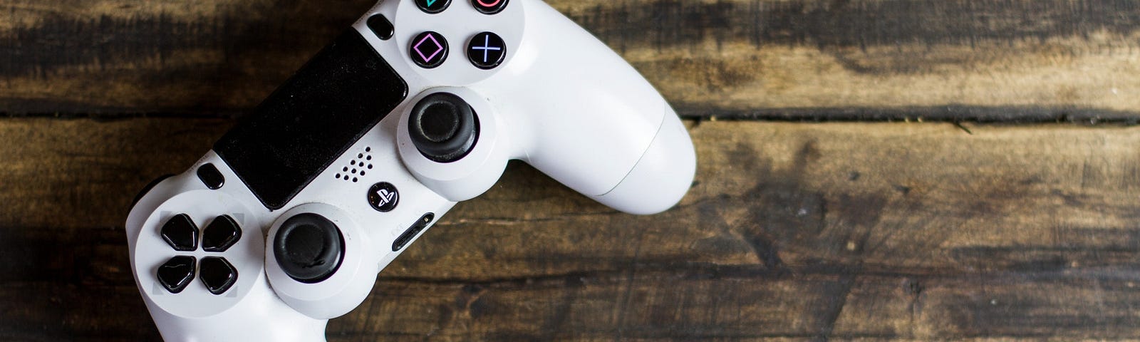 White gaming controller for Playstation on a wooden table