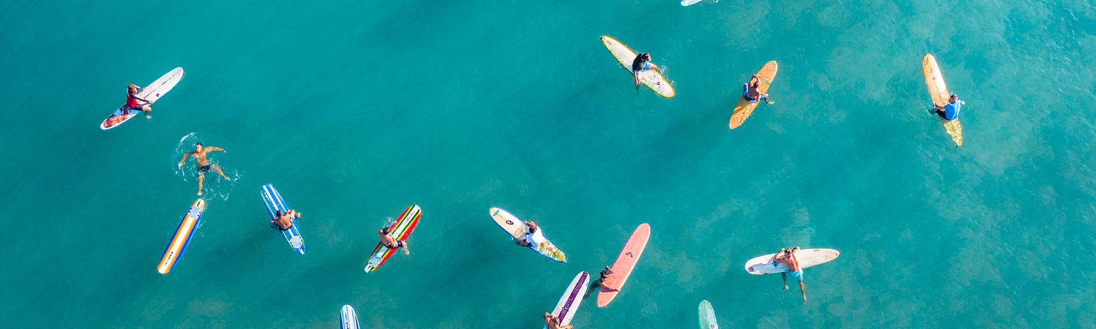 An arial view of surfers floating on a calm blue sea.