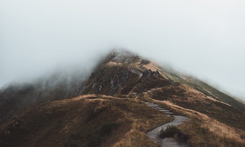 Twisting path along a mountain ridge, disappearing into fog