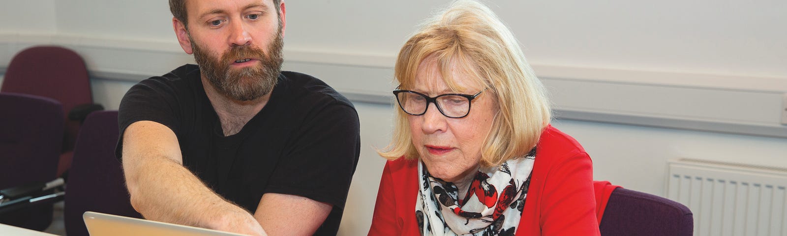 Man and woman sitting at desk looking at laptop