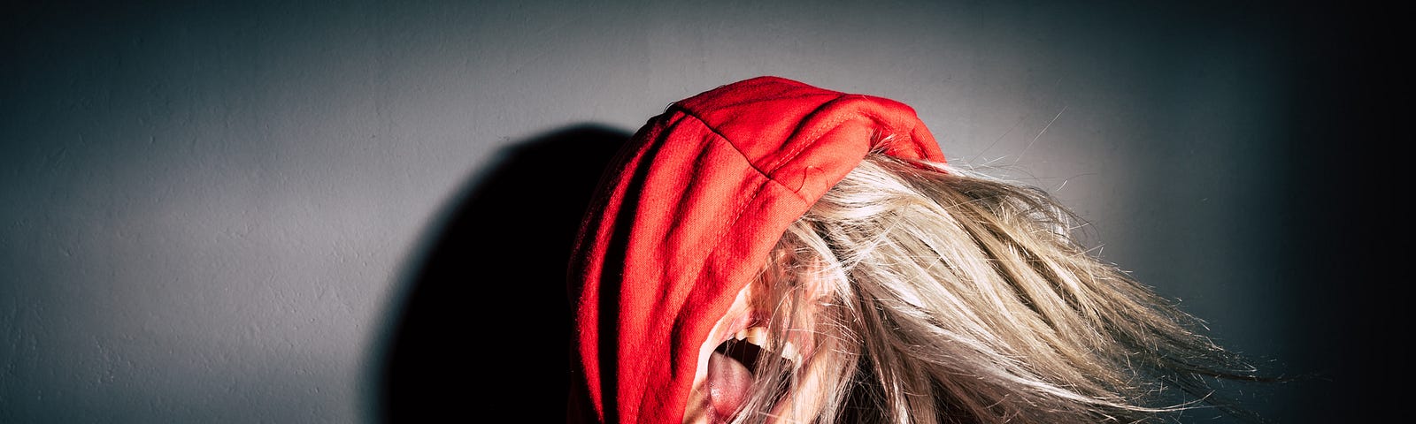 A blonde woman in a red hoodie screams.