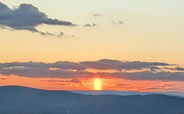 A wide shaft of sunlight reaching from the mountaintop to the clouds.