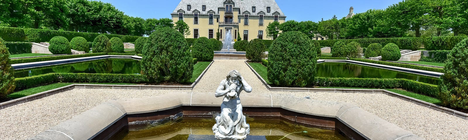 Front view of Oheka Castle with elaborate statue in the middle of a fountain