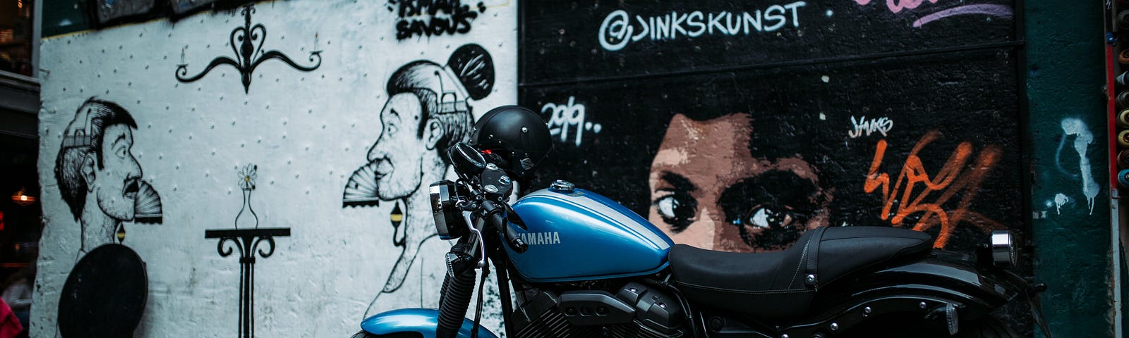 Motorcycle in front of a graffiti wall at night.