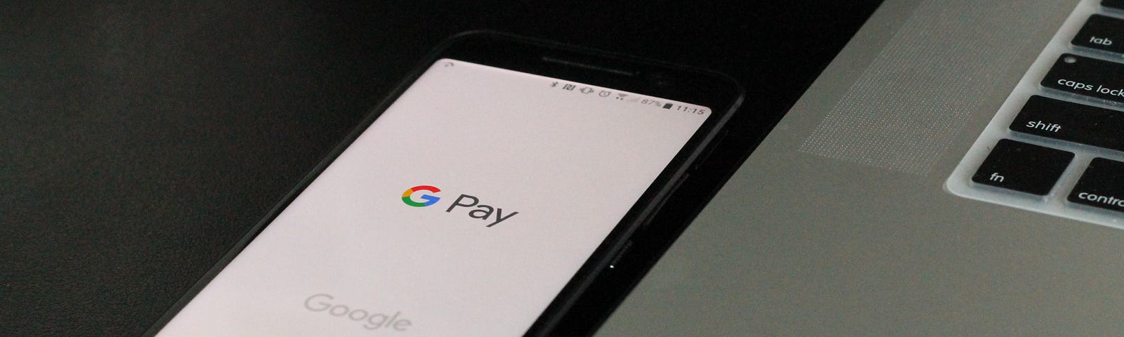 Picture of a mobile phone with the Google Pay app open next to a Mac.