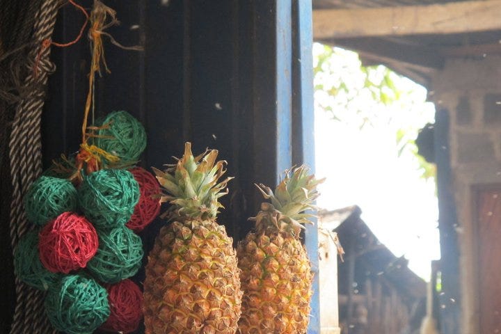 Dos piñas y unas pelotas de lana de colores en la ventana de una casa de campo