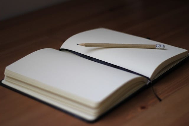 Open Journal of blank pages with a pencil on it.