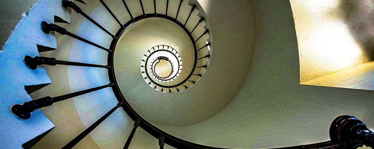 An image of a spiral staircase leading upwards towards light