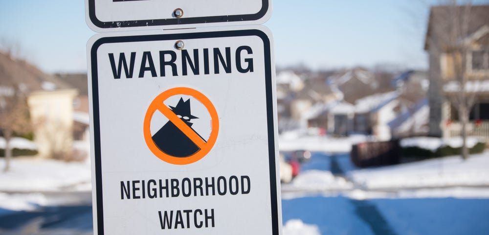 Neighborhood watch sign in a snowy Midwest suburb.