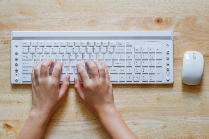 White keyboard and mouse with hands typing.