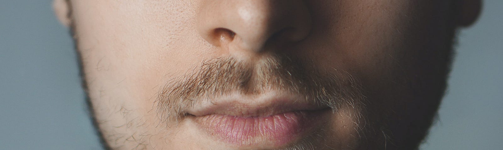 The lower half of a man’s face with mild facial hair.