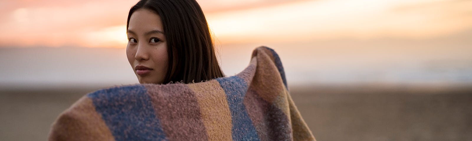 Young woman posing on beach with a blanket