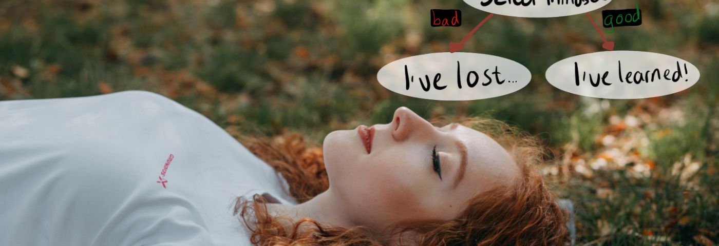 Woman with curly ginger hair and white T-shirt, lying on blanket on grass that shows the season is changing (into autumn). Annotations: Fired? Select mindset. Bad → I’ve lost. Good → I’ve learned.