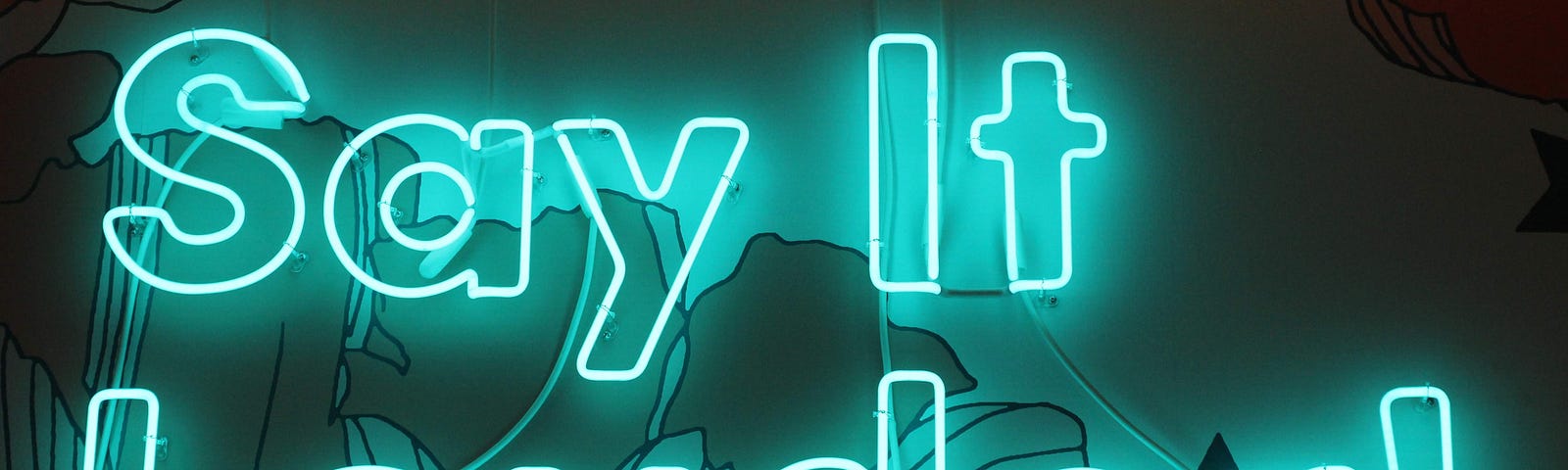 A blue neon sign reading “Say it Louder!”