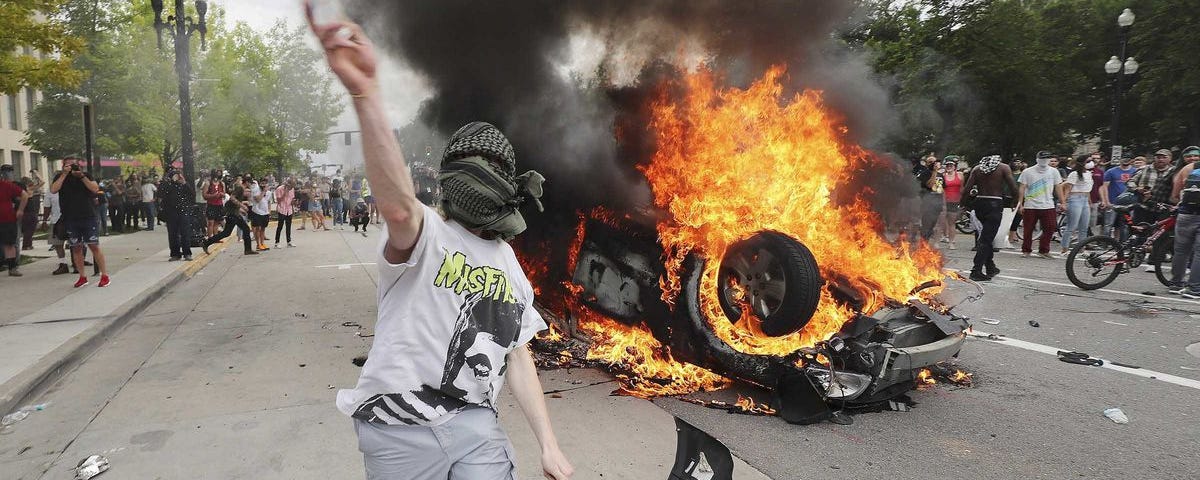Protestors gathered around a burning, overturned car.