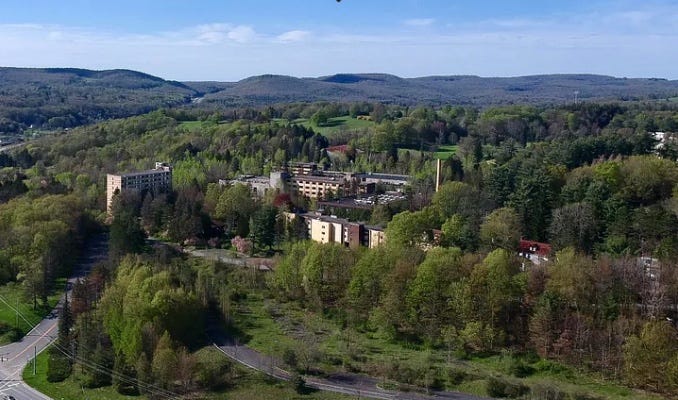 Aerial shot of a Catskills Mountains resort — resort buildings in the midst of forest and hills.