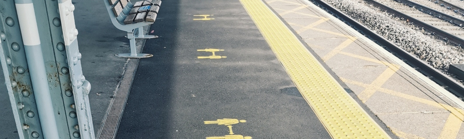 Image of a train platform, showing yellow paint and encouraging social distancing.