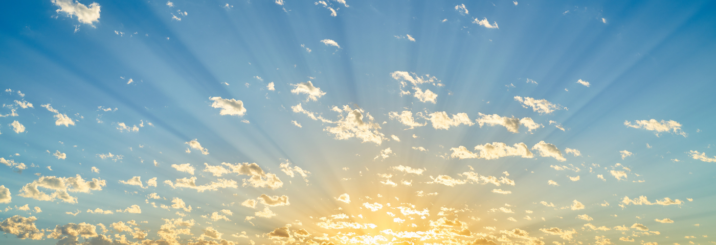 Sunrise over the mountains with blue sky, clouds, and shades of gold