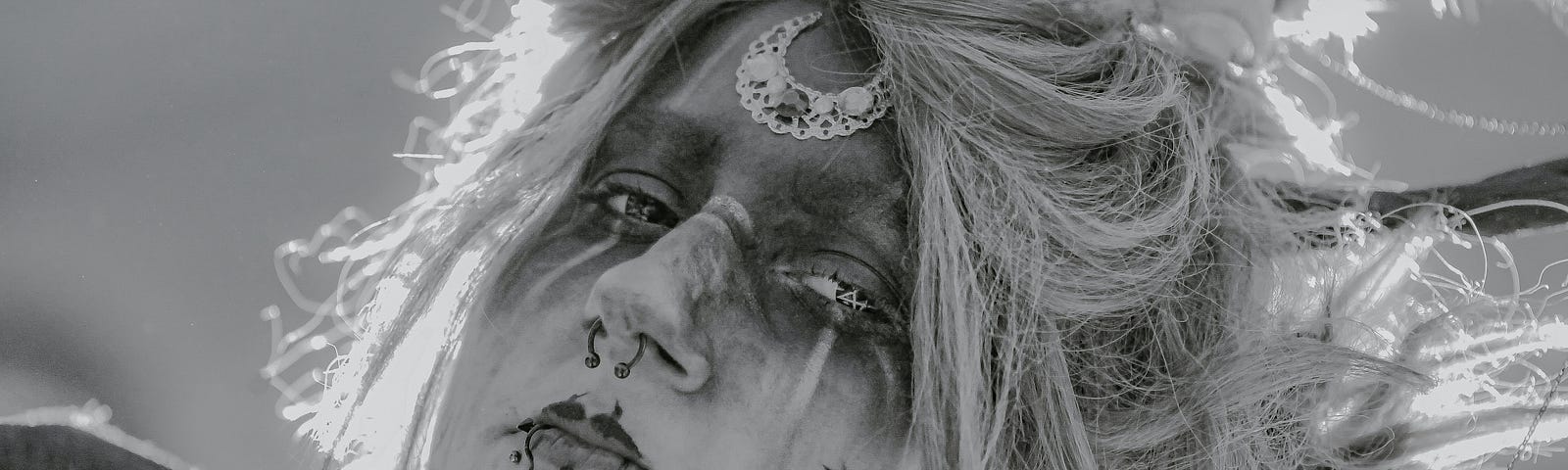 Black and white photo of tattooed, pierced face.