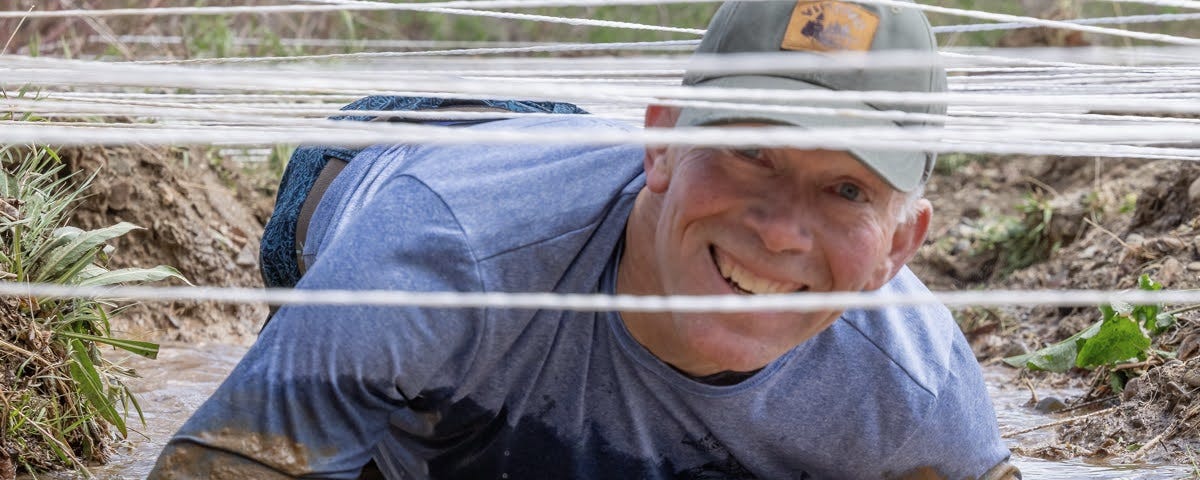 The author smiles as he crawls underneath a web of white cord and into a mid-pit