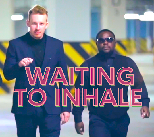 Two men dressed alike and walking toward the camera. The words “Waiting to inhale” are superimposed.