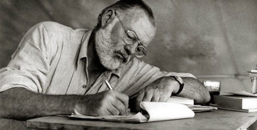 Black-and-white photo of Ernest Hemingway writing in Kenya