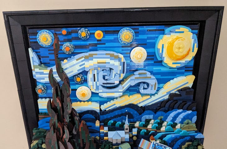 The completed LEGO set of the Starry Night painting by Vincent Van Gogh hangs on a beige wall.