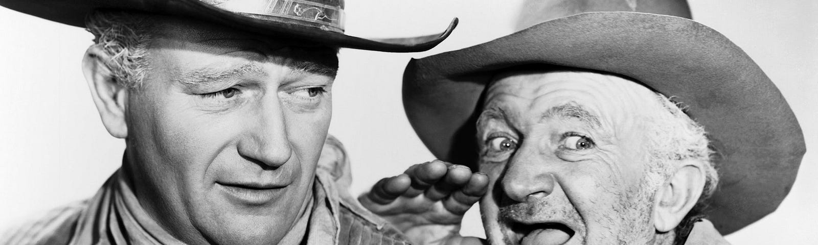 The actor John Wayne with Walter Brennan in costume, wearing cowbiys hats.