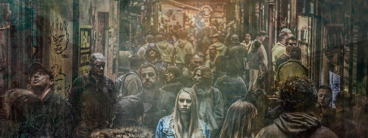 Blonde woman among a crowd of grey-brown looking people, looking like she is lost or “lonely in the crowd”.