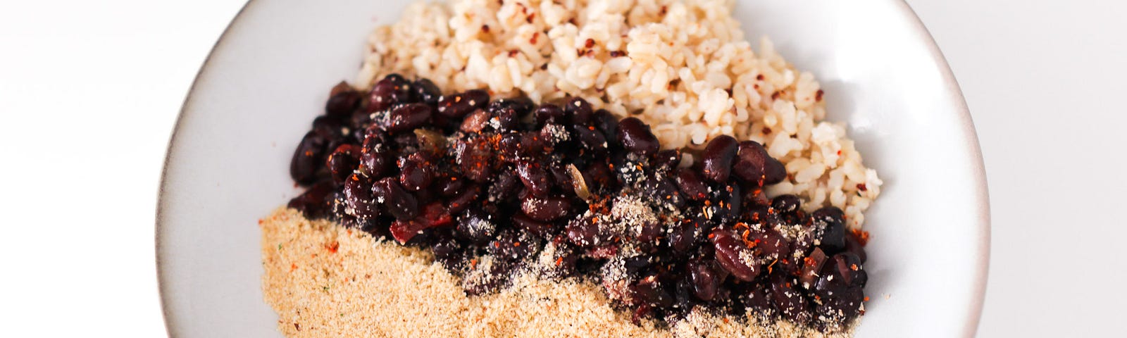 A serving of feijoada (middle) with brown rice and quinoa (top) and farofa (bottom).