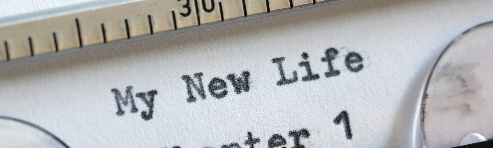 A typewriter with a piece of paper in it that has “My New Life Chapter 1” typed on it