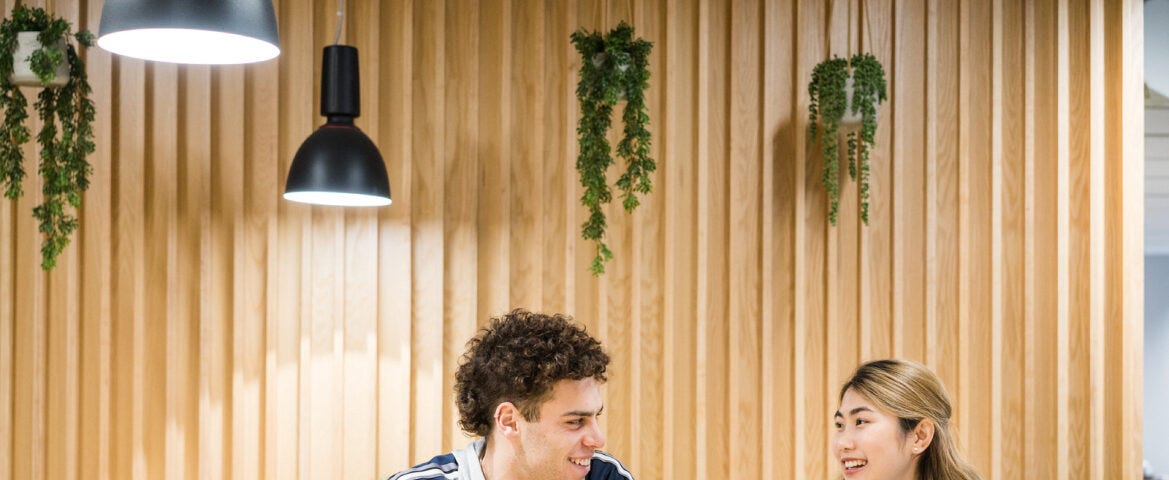 two students sat chatting to each other with a cup of coffee.