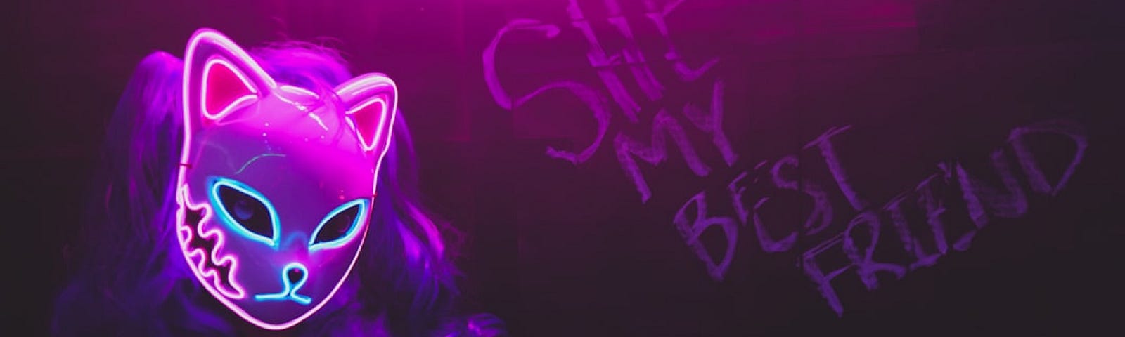 A woman wearing a mask displaying a cat’s face in neon lights. It casts the wall behind her in eerie purple and shadows.