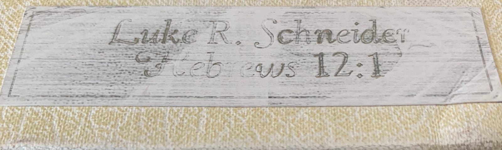 A name plate on a book, engraved with “Hebrews 12:1”