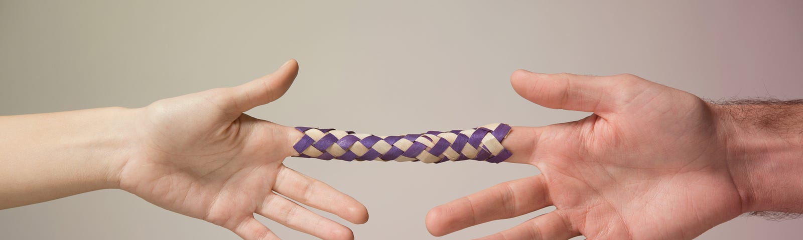 Two hands locked in a Chinese Finger Trap