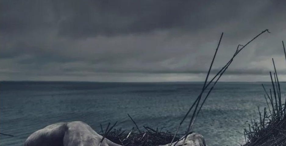 Hands reaching over the edge of a cliff, with the sea behind