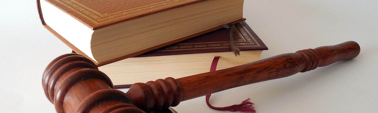 A wooden gavel and sound block are shown at the bottom of the image. Two books with gold leaf designs on their covers are stacked behind the gavel.