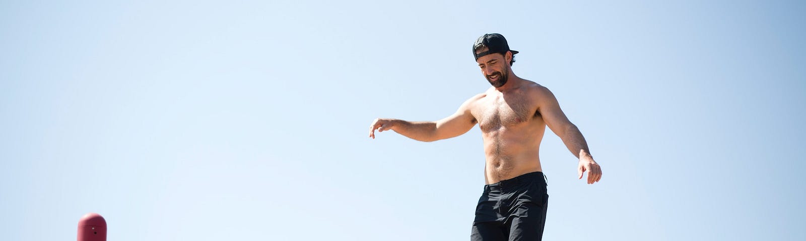 A muscular man on a balance beam.