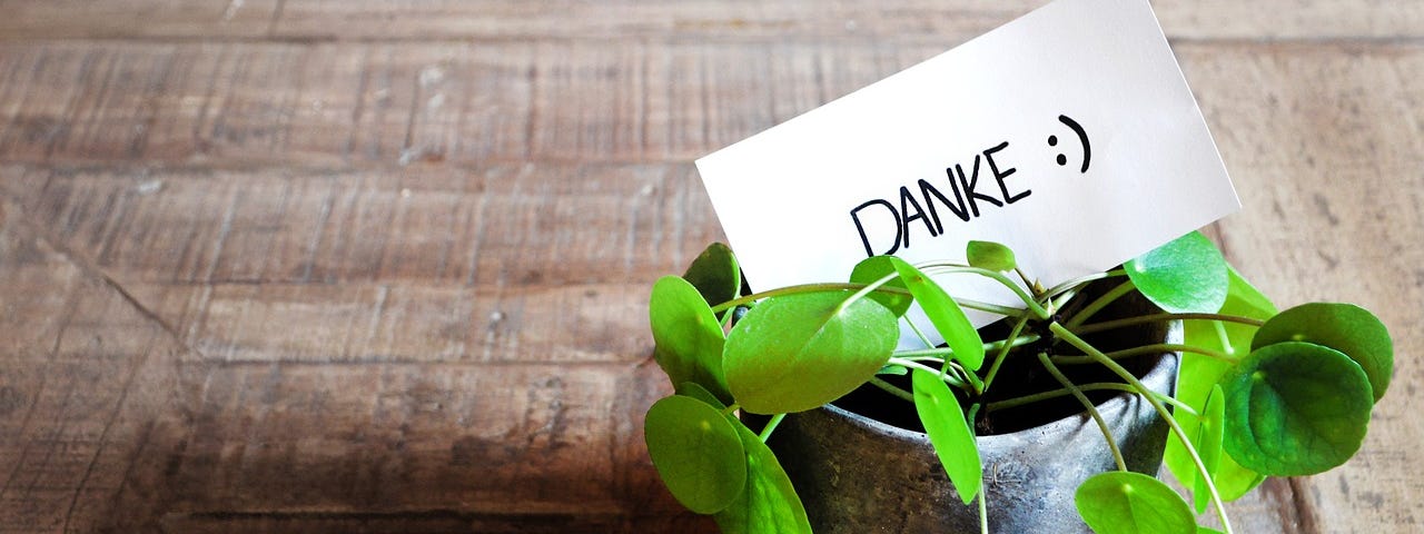 A small bucket of green sprouts on the table with the card “Danke” written on it.