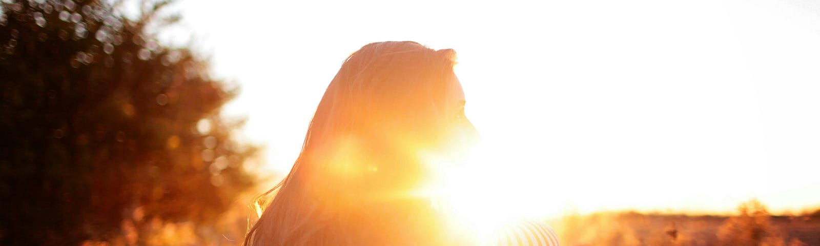 Rear view of woman standing on a balcony during sunset.