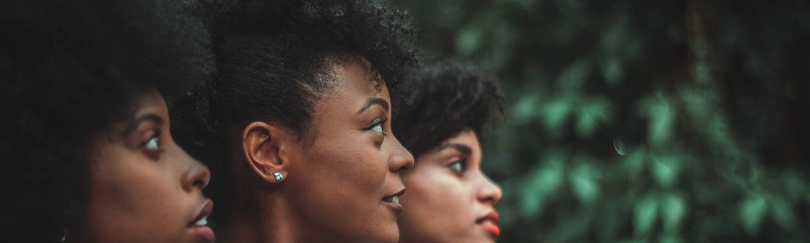 Three Black women looking over their shoulder