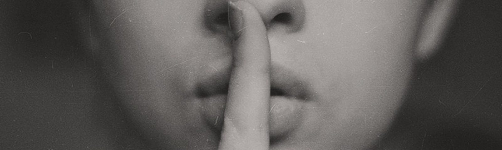 Woman with finger to mouth to say shhhhhh in black and white
