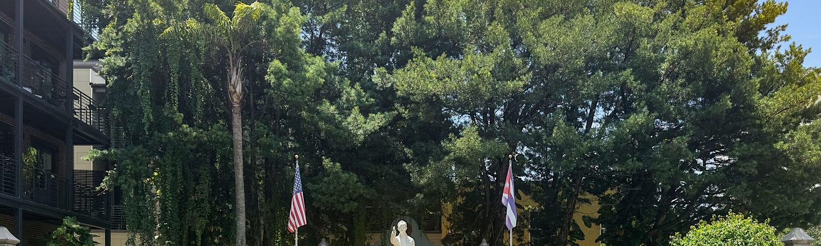 A statue of José Martí stands in the center of a grassy park with a paved pathway leading towards it.