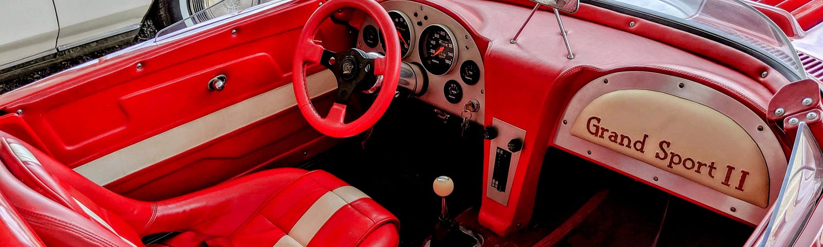 This shows the inside of a Corvette convertible. It’s red and white.