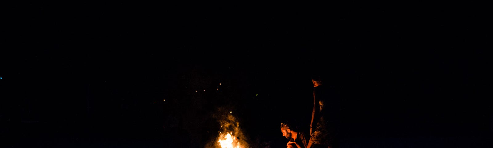 Two people having a campfire.