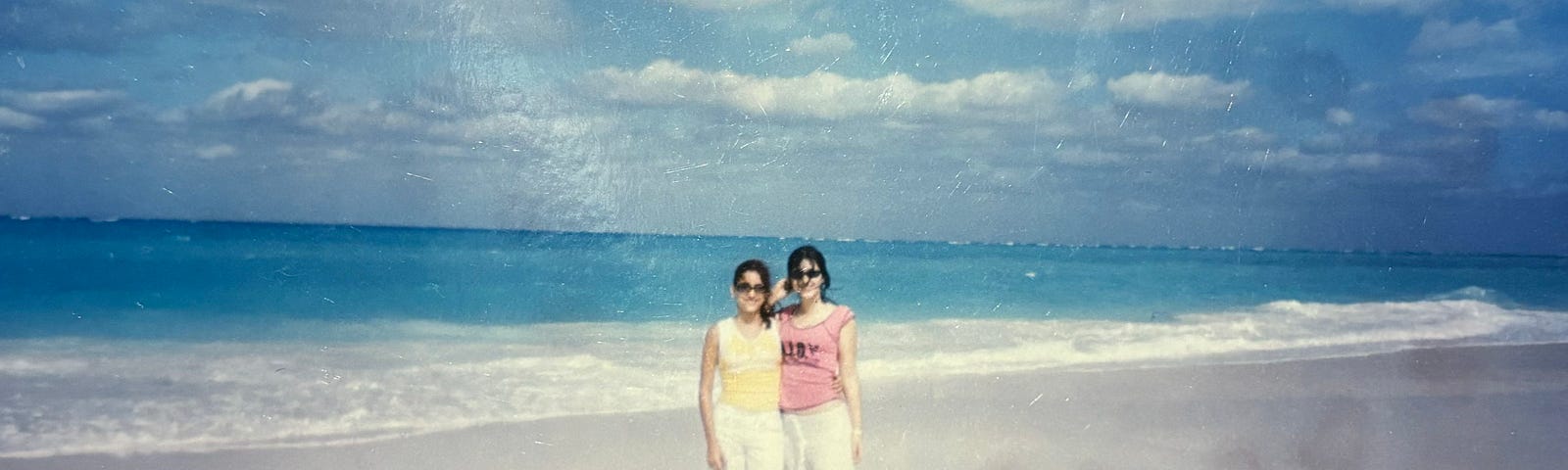 Two young women stand on a white sand beach