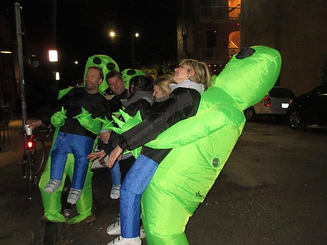 Green aliens pick up human men — a Halloween costume