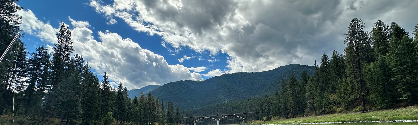 Wide river with bridge and mountains in the distance.