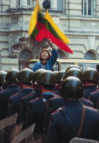 A girl holding a flag of independent Lithuania above military police of the USSR