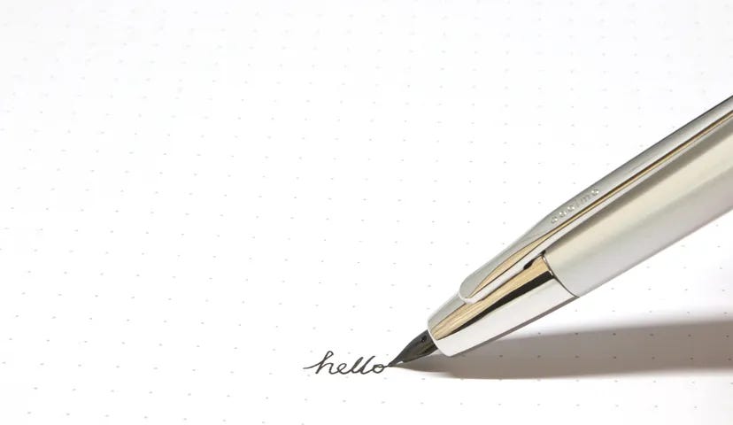 The tip of a beautiful fountain pen writing the word “hello” (Real Insight)